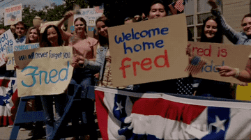 Archie and Veronica look outside and see people with signs welcoming Fred home