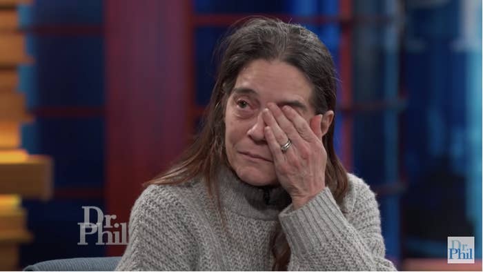A woman on TV covers one eye with her hand as she weeps