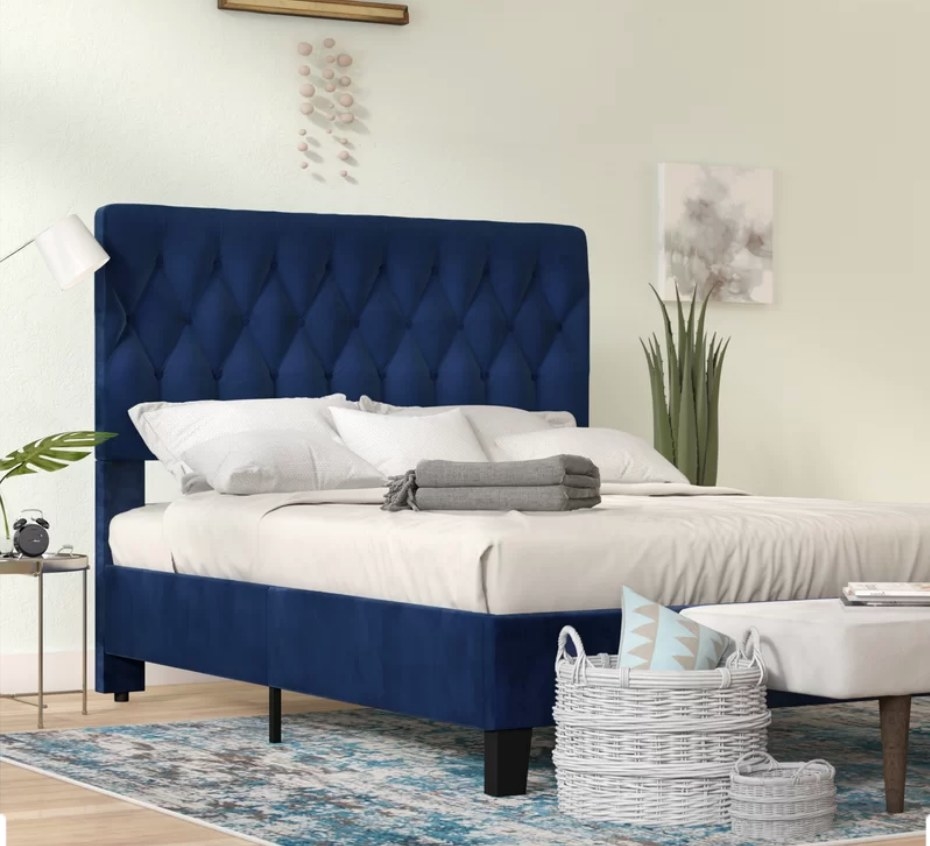 Navy blue upholstered bed frame with tall, tufted head board 