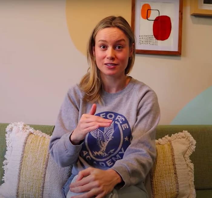 Brie in a sweatshirt and jeans talking on a couch