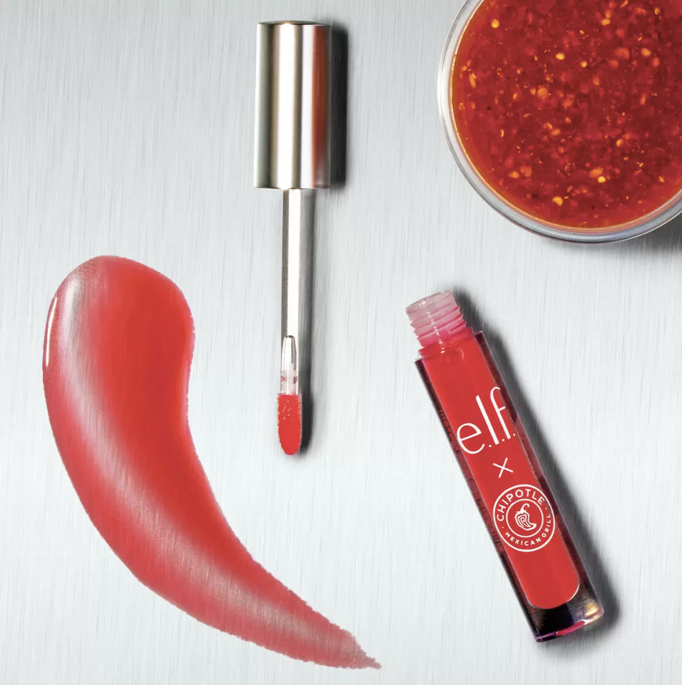 A clear lip gloss bottle with the Chipotle and E.l.f. logos with a brush swatching a chili shape