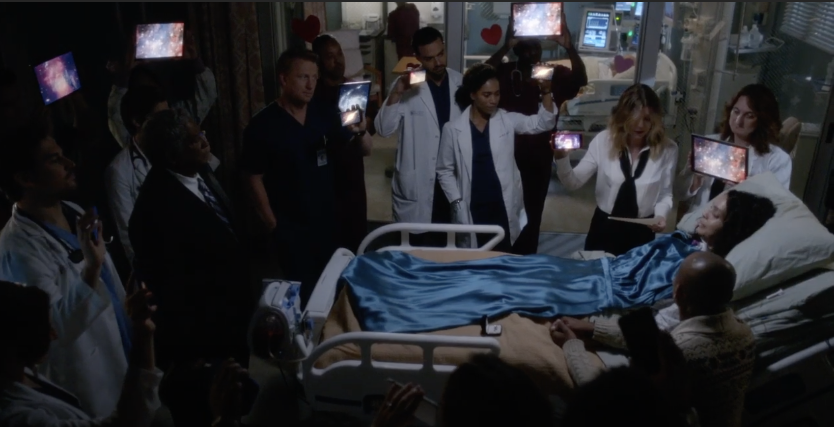 the doctors hold up ipads and phones with stars above Natasha and Garrett