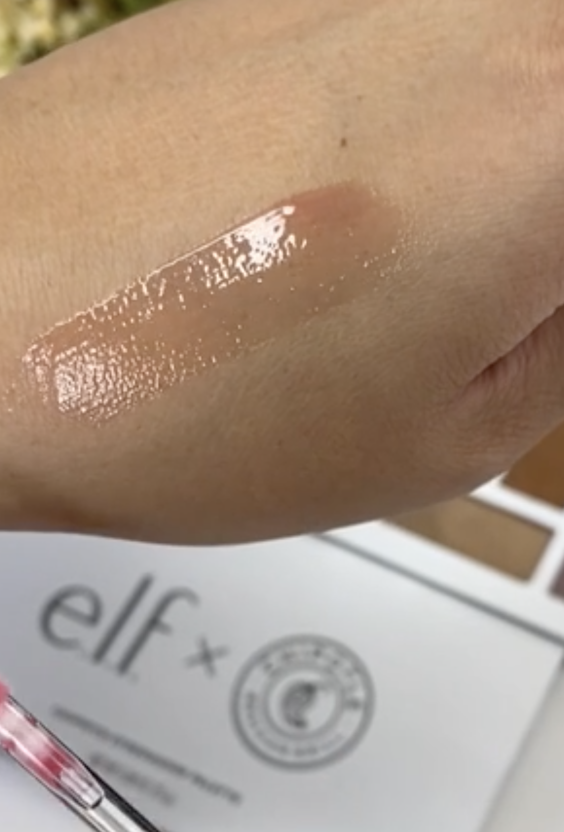 A transparent red sheer gloss on a person's hand