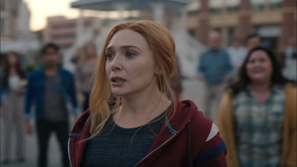 Wanda wears a gray shirt under a red, white. and blue track jacket