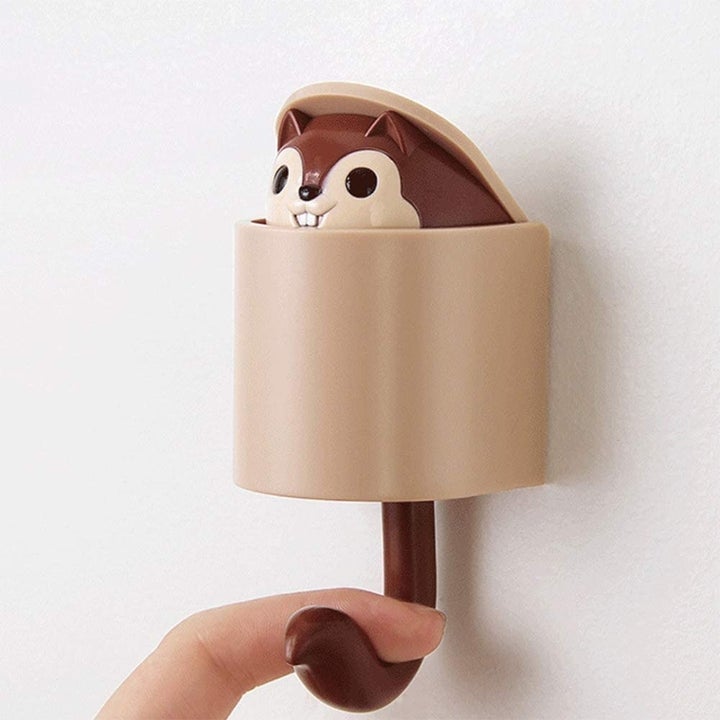 Model pressing down on tail-shaped hook to make squirrel figure pop up from key holder