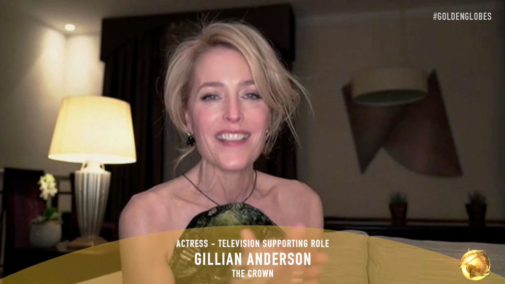 Gillian Anderson smiling during the virtual Golden Globes, with the text &quot;Actress — television supporting role, Gillian Anderson, The Crown&quot;