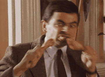 Gif of Mr. Bean excitedly eating chicken thighs 