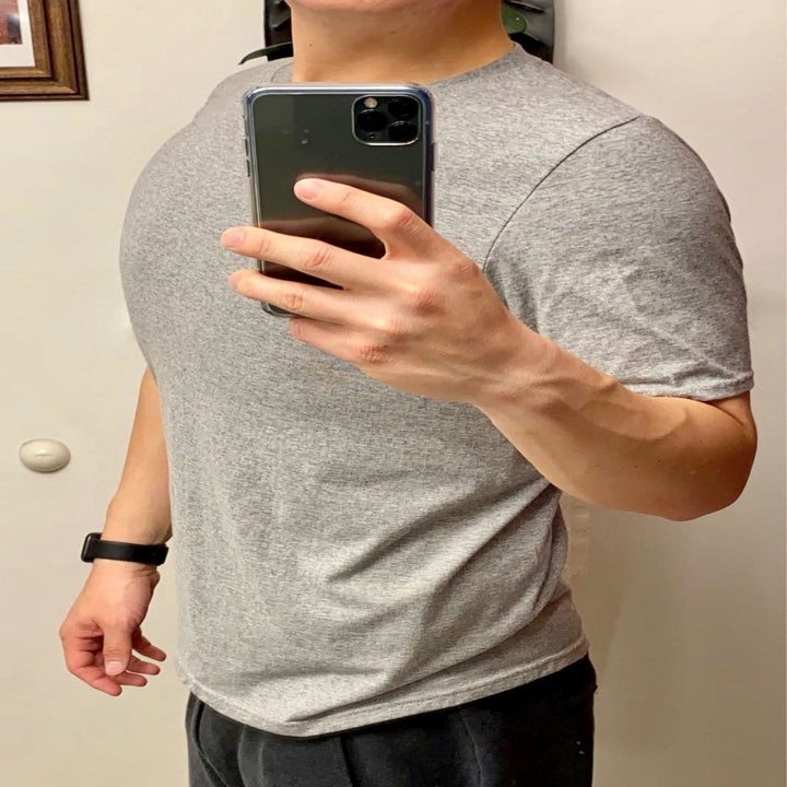 same reviewer taking a selfie while wearing the grey athletic shirt