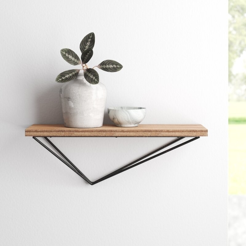 wood shelf with triangle-shaped bottom in black metal on a wall