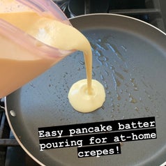 Pouring crepe batter out of the container easily into a greased pan