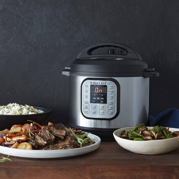 Silver and black Instant Pot pressure cooker next to dish with steak and potatoes