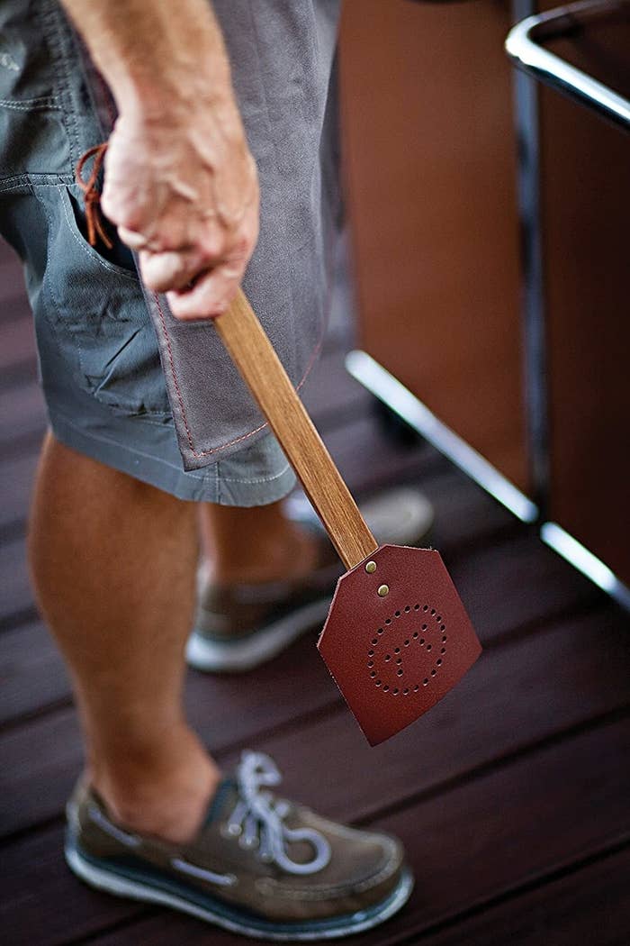 A person holding the leather fly swatter