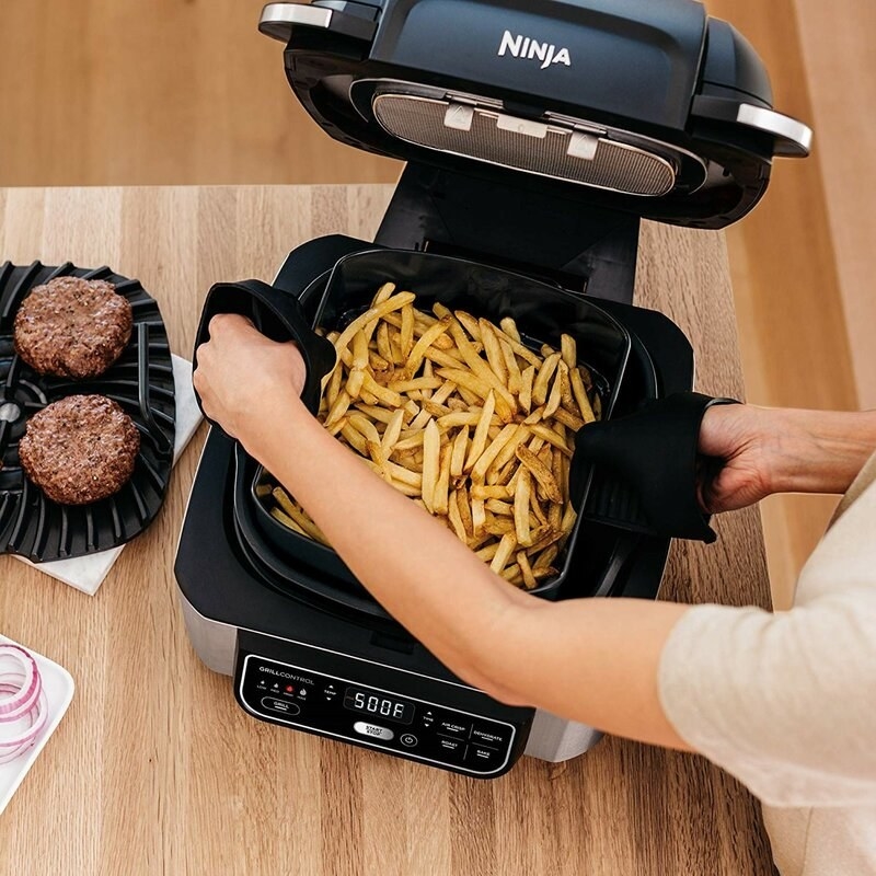 someone making french fries with the air fryer/grill