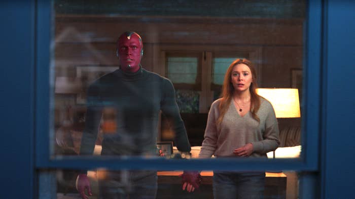 Vision and Wanda hold hands while looking out the window at something