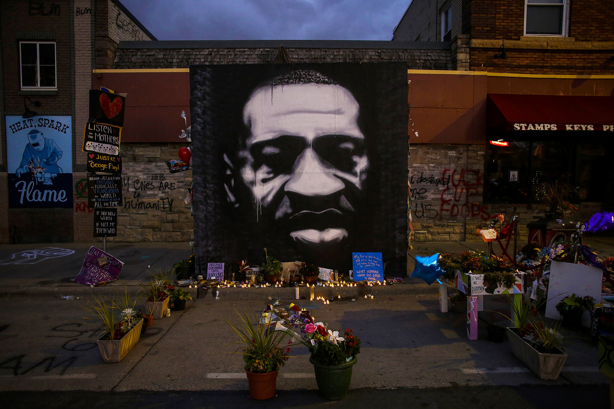 The George Floyd memorial outside Cup Foods, featuring a mural of Floyd&#x27;s face, candles, and flowers