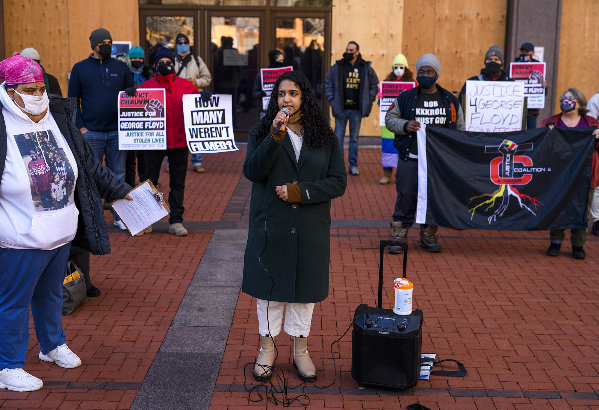 A person speaks into a microphone among a crowd of demonstrators at the government center