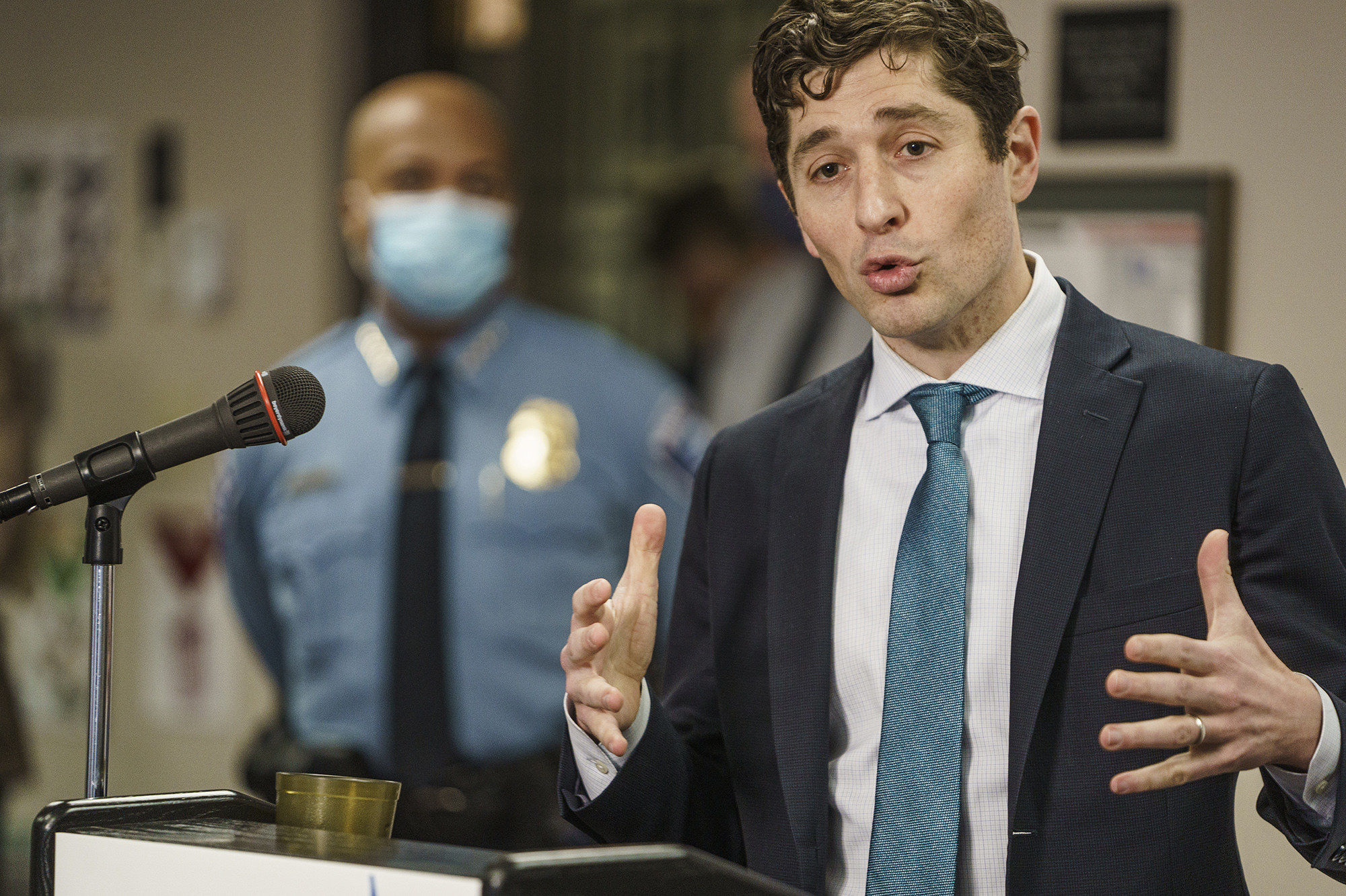 Mayor Frey speaks at a podium while Chief Arradonda is out of focus in the background