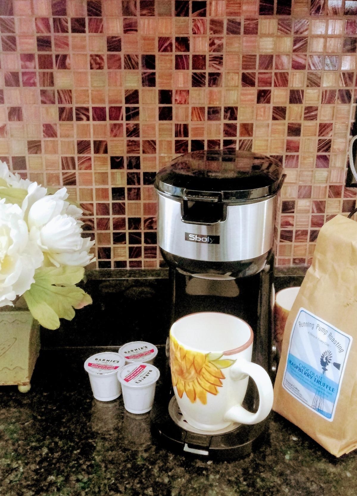black single-serve coffee maker with floral cup below it 