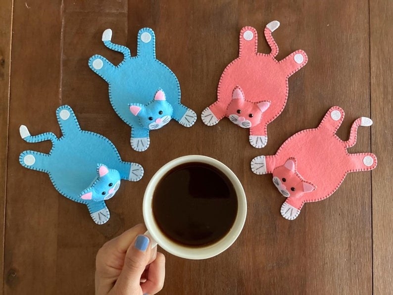 Model holding coffee cup with four cat-shaped coasters on table