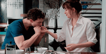 Christian licking food off of Ana&#x27;s hands in a sexual fashion 