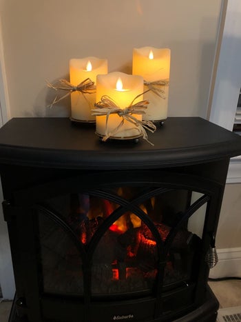 reviewer's three flameless candles in triangle with twine above a wood-burning fireplace
