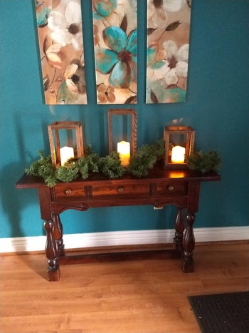 same candles in glass cases decorated with a pine garland on a reviewer's table