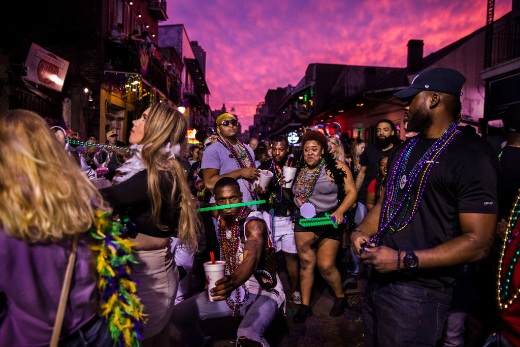 Bourbon Street filled with revelers wearing beads and feather boas as they drink and have a good time