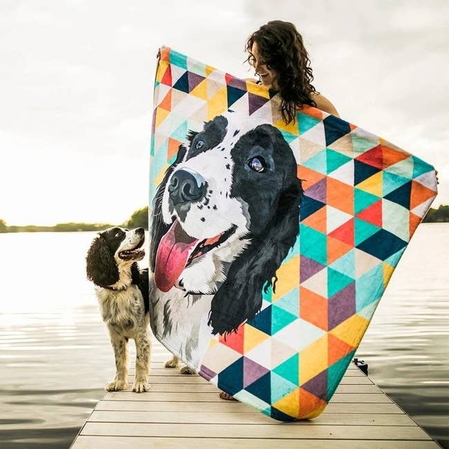 Spaniel standing next to a person holding a colorful geometric print with the dog's portrait on it