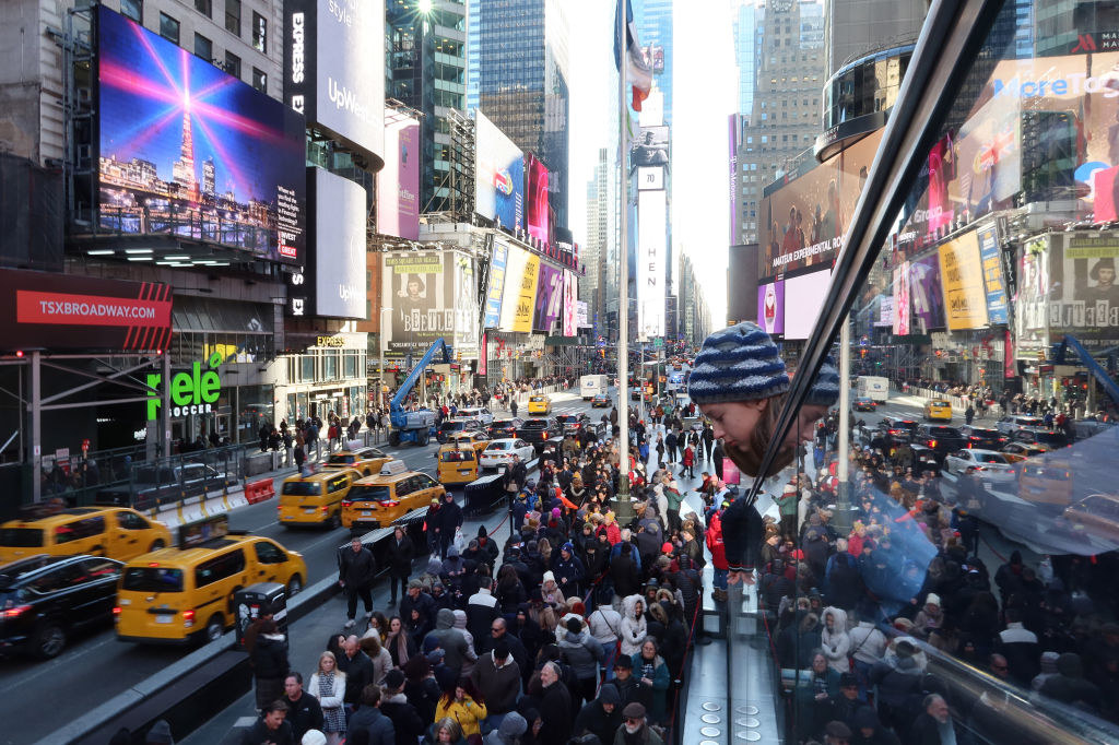 Times Square filled with people as taxis and other vehicles drive through