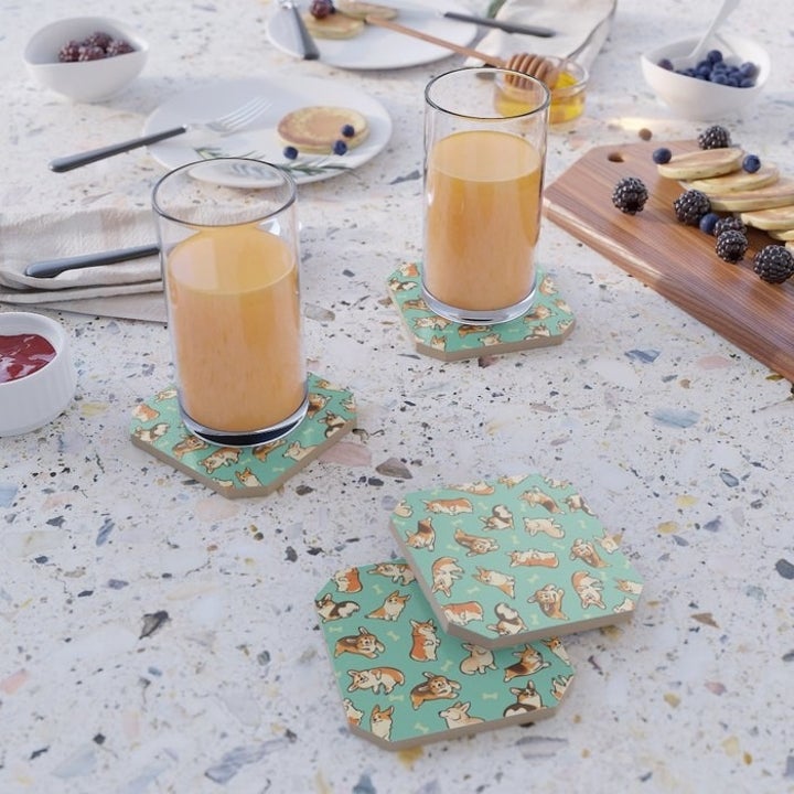 Four coasters with corgi patterns placed on table with glasses on top