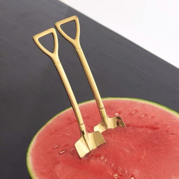Two shovel-shaped spoons inserted in watermelon