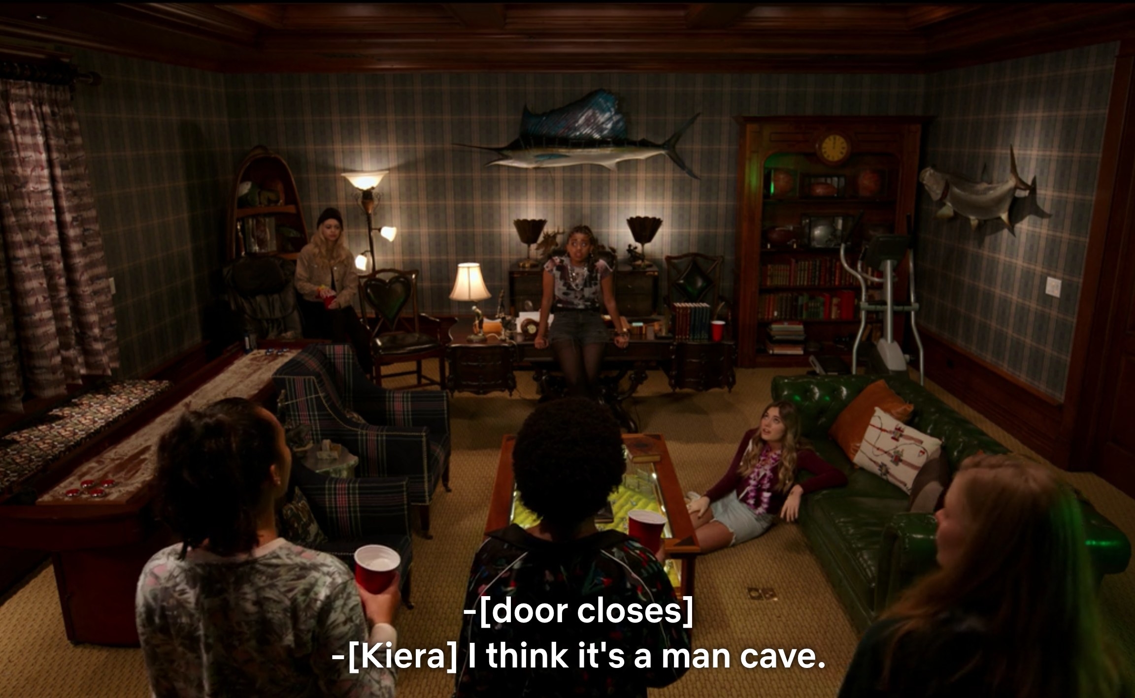 Girls in the Moxie club gather in a dim room with plain, drab decorations, and Kiera says, &quot;I think it&#x27;s a man cave&quot; as the door closes