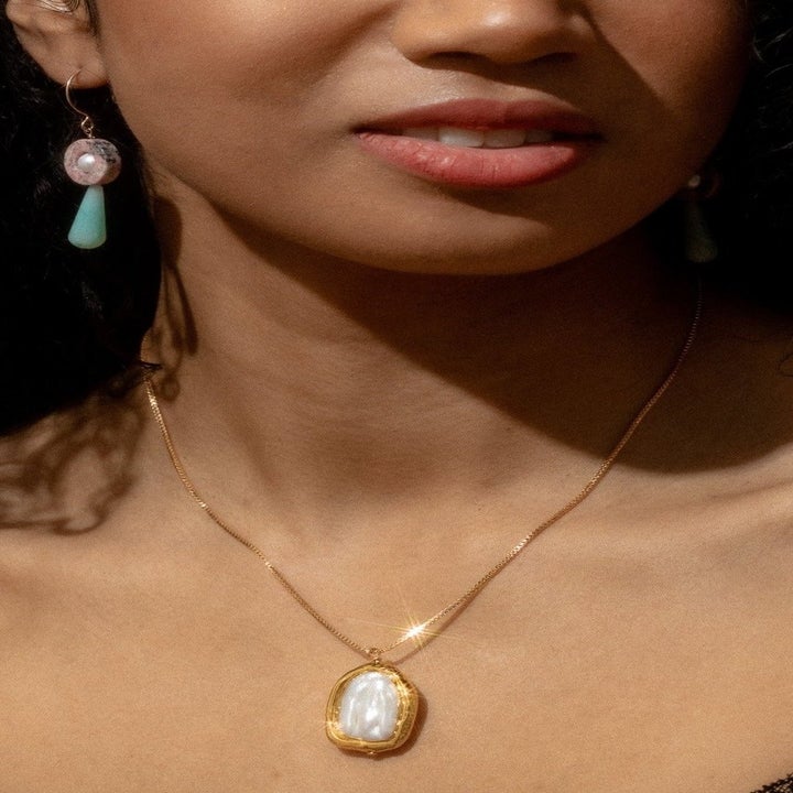 a model wearing the pendant necklace in gold