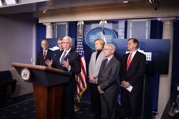 Former Vice President Mike Pence speaking in the White House Press Briefing room surrounded by Dr. Fauci and other people