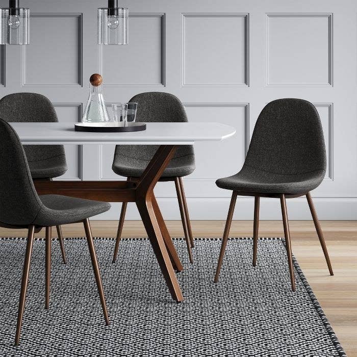 grey upholstered bucket seat dining chair with wooden legs next to a dining table