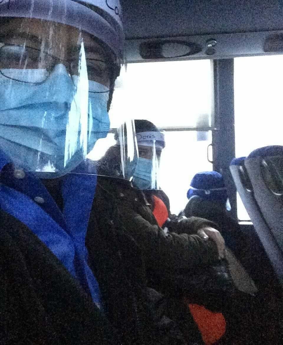 Two people on a bus with masks and face shields