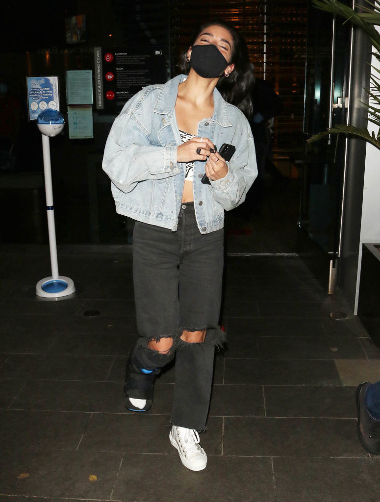 Charli leaving a building while wearing a face mask and a foot brace