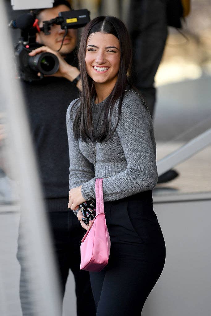 Charli smiling while a man films her outside