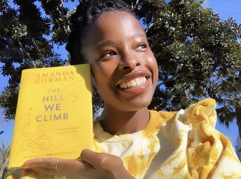 Amanda smiling and holding her book &quot;The Hill We Climb&quot;