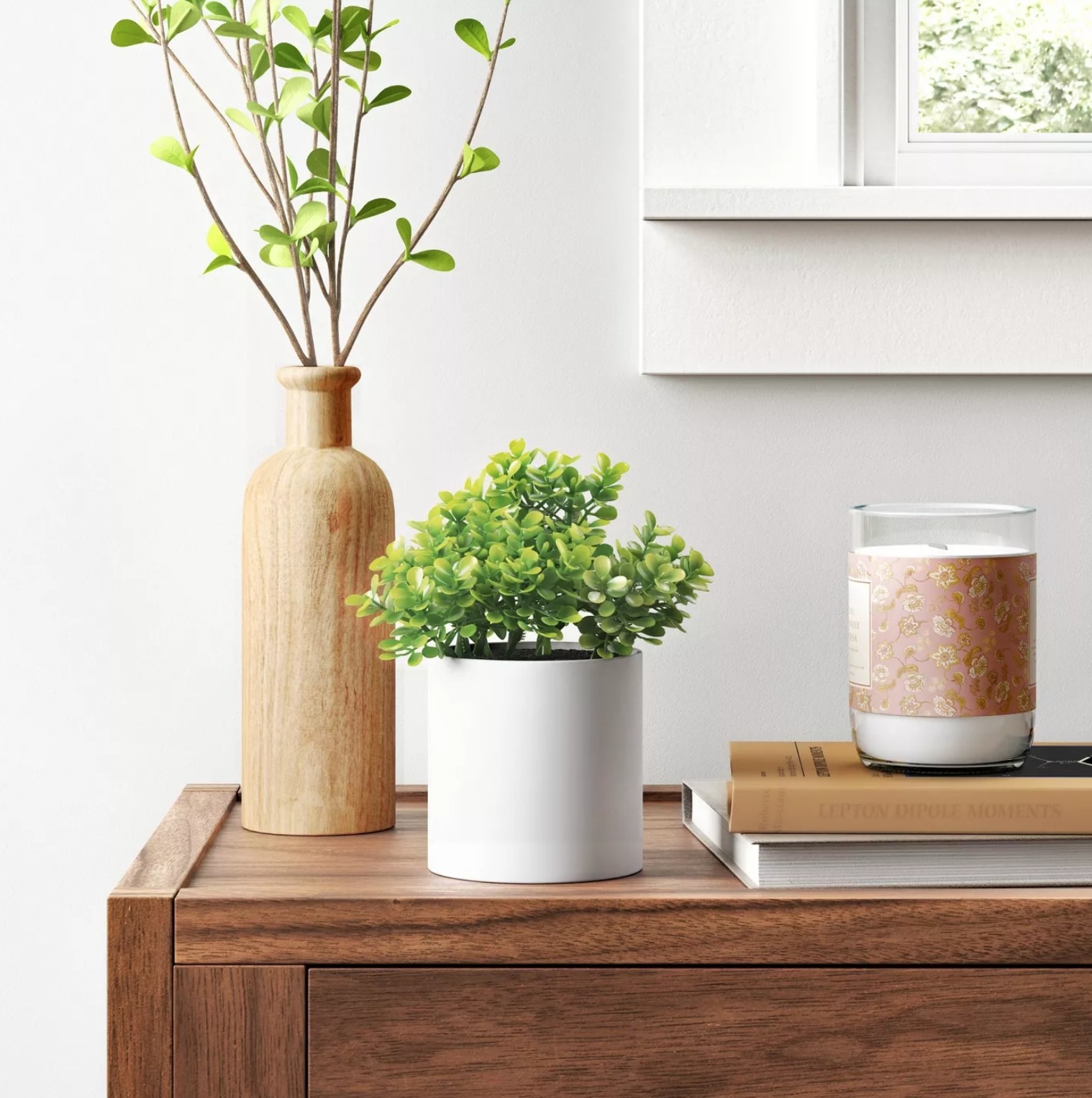 The box plant in a white planter on a desk with other decorations