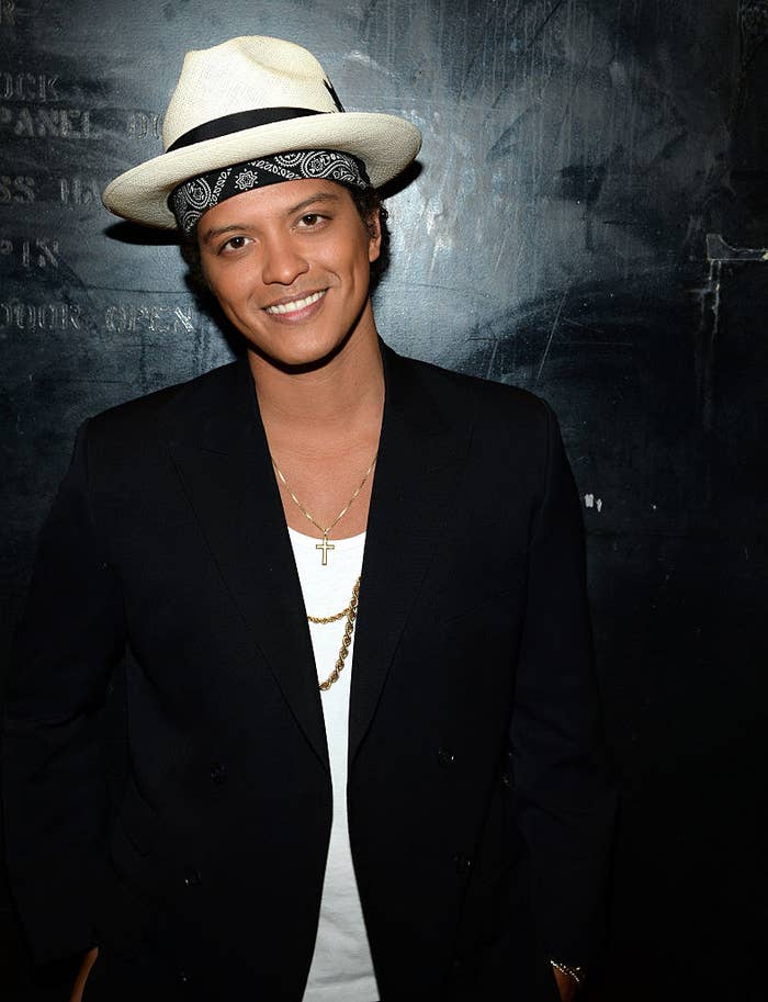 Bruno rocking a fedora, bandana, a blazer, and chains