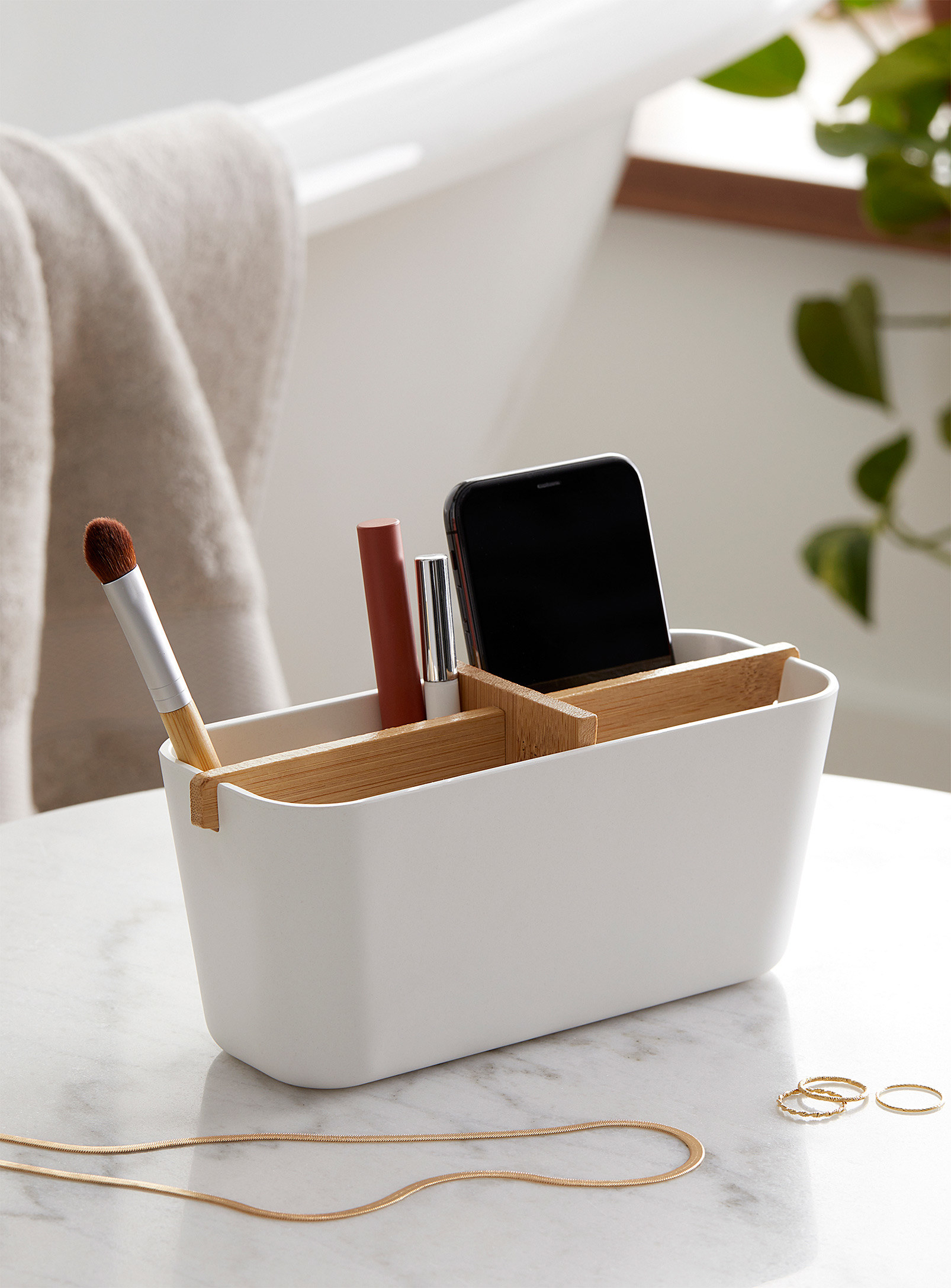 A small rectangular basket with makeup and a phone nestled inside