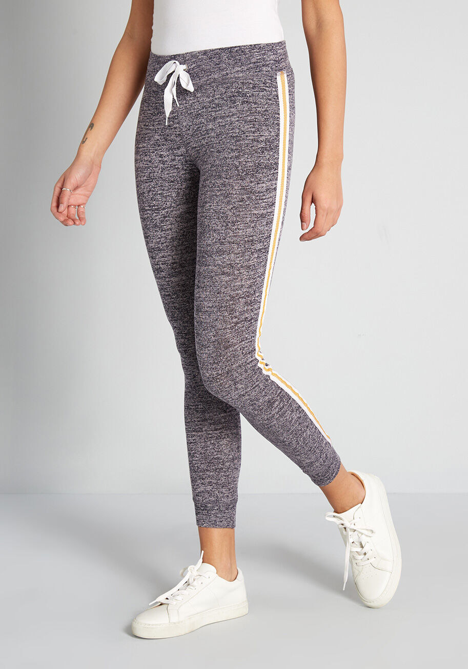 a model wearing the gray sweatpants with a white and yellow stripe on the side