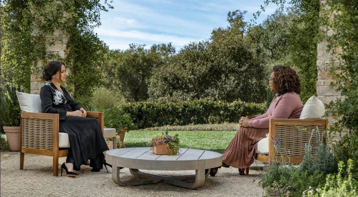 Meghan and Oprah sitting across from each other in an outdoor space