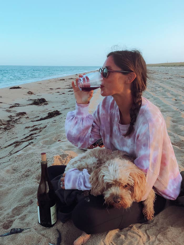 Me drinking wine on the beach with my sleepy dog.