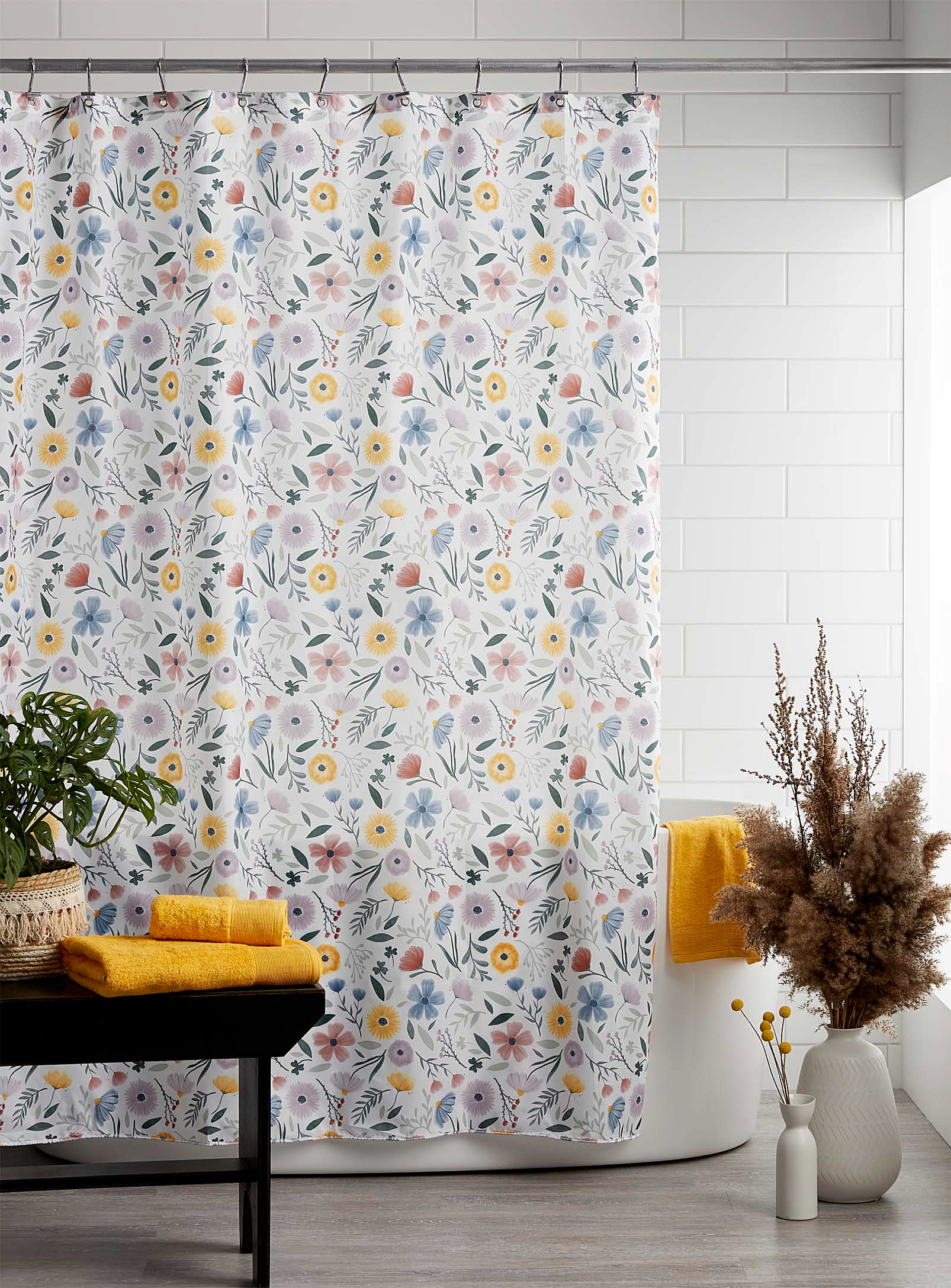A floral shower curtain hanging around a tub 