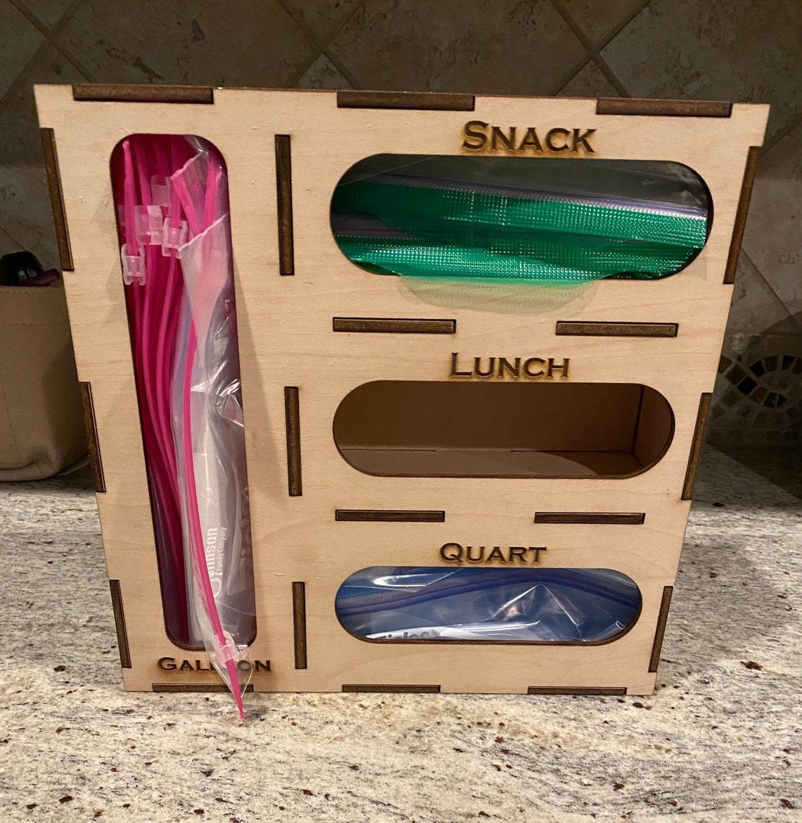 The wood organizer, which has slots for different size plastic bags