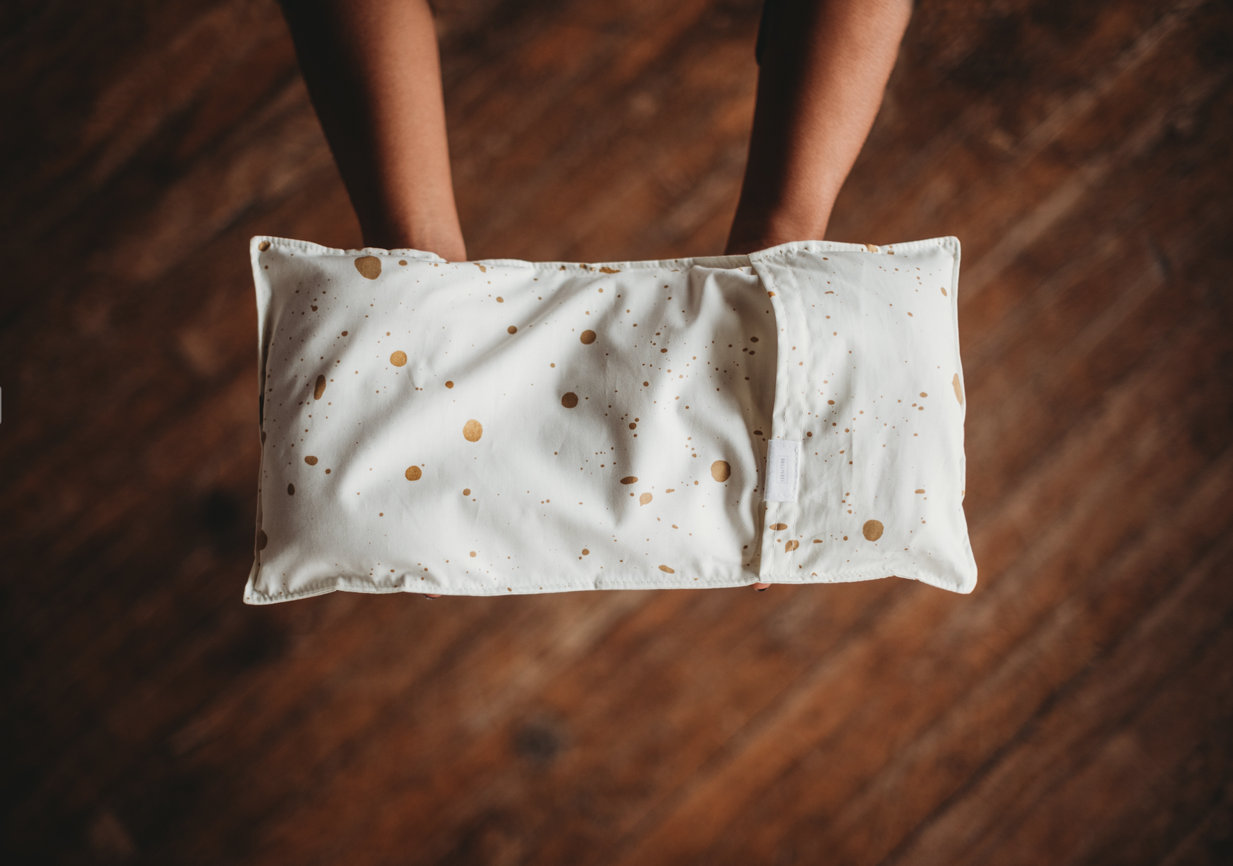 Model holding a white small pillow shaped pack with gold speckle pattern 