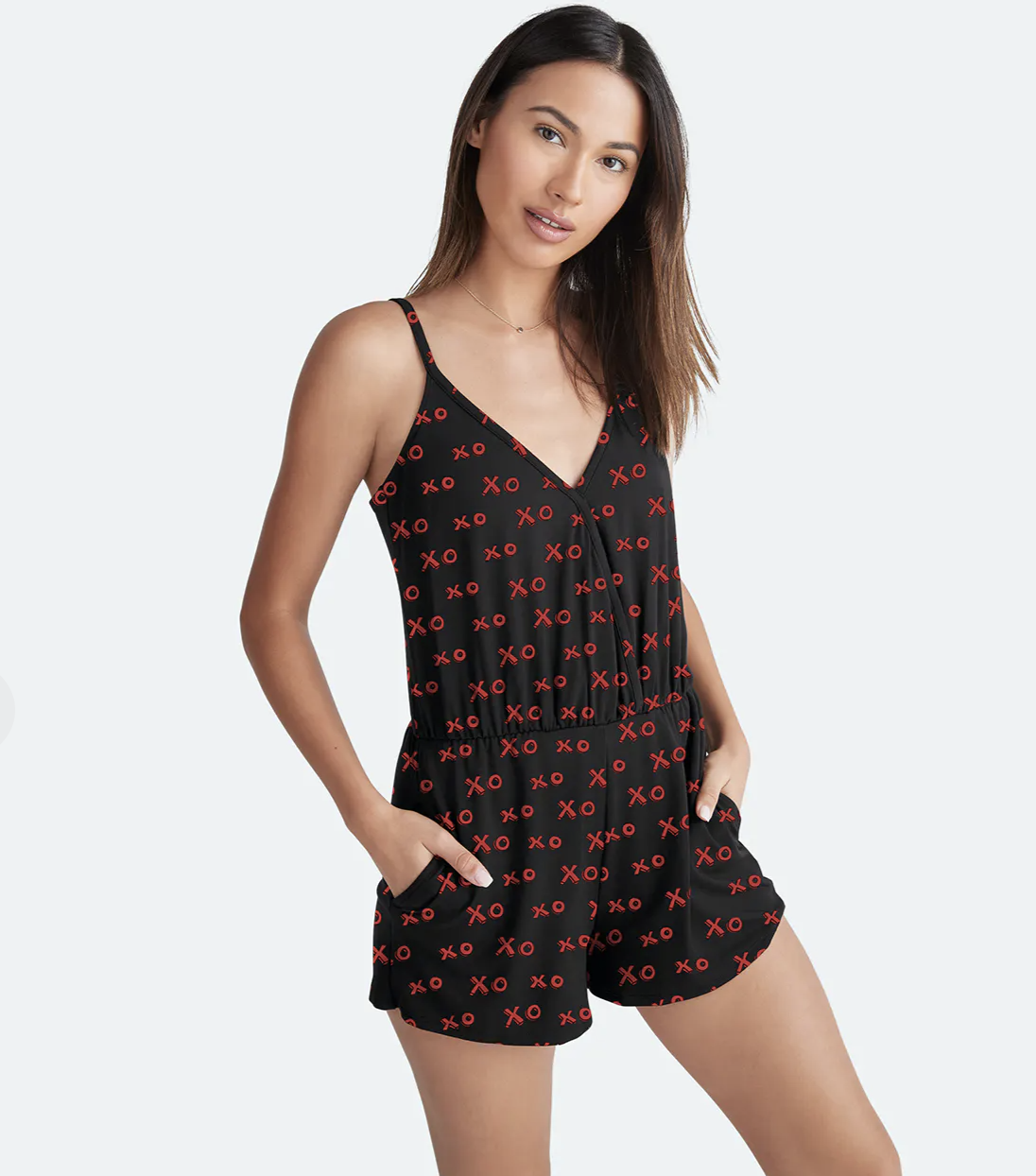 model wearing the tank top and shorts romper in black with &quot;XO&quot; in red all over it