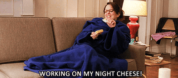 Liz Lemon on the couch in a snuggie singing &quot;working on my night cheese&quot; 